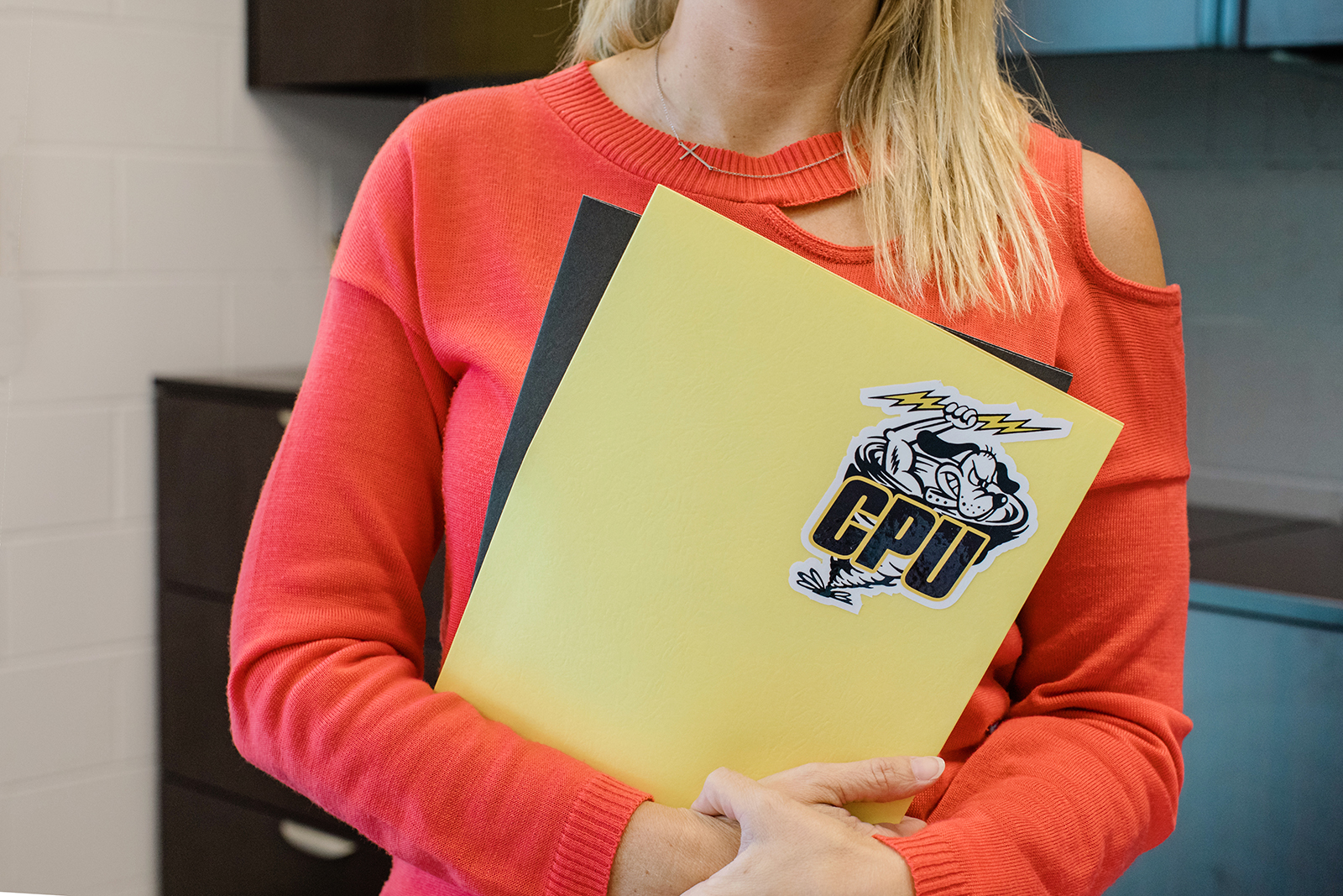 Teacher holding a yellow folder with the CPU logo on it